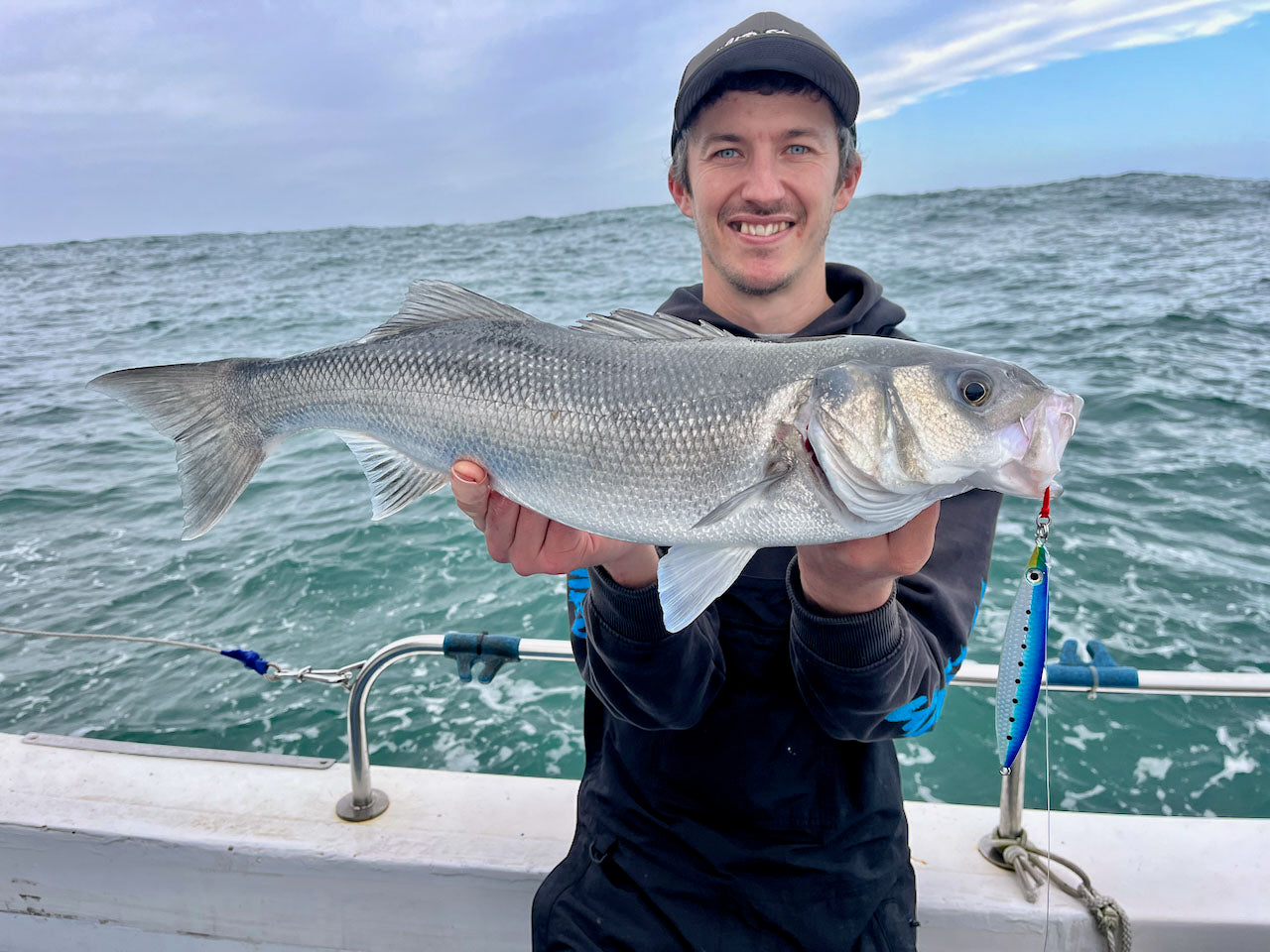 Liam with a Bass caught jig fishing with a Fish Nugz Slayer Sardine Shimmer